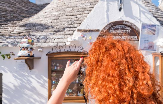 Red hair tourist photographing in Alberobello, Apulia - Italy.