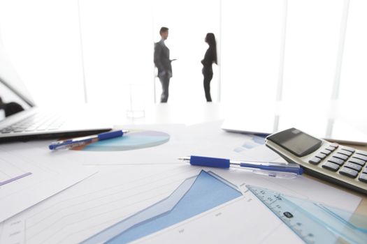 Financial reports, calculator and laptop on table in office