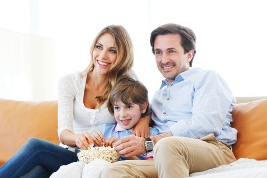 happy family watches movie while sitting on the couch