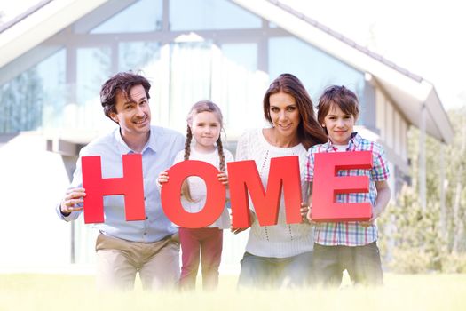 happy holding home letters in front of their house