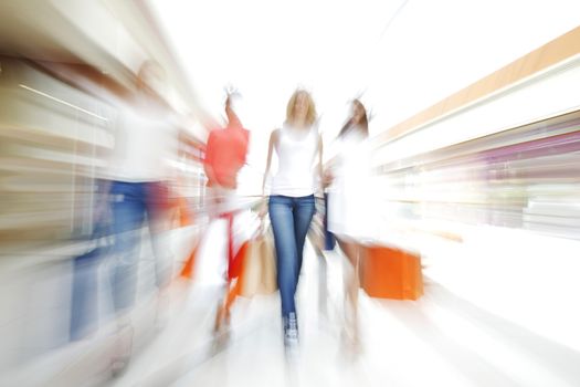 Women walking fast in shopping mall with bags