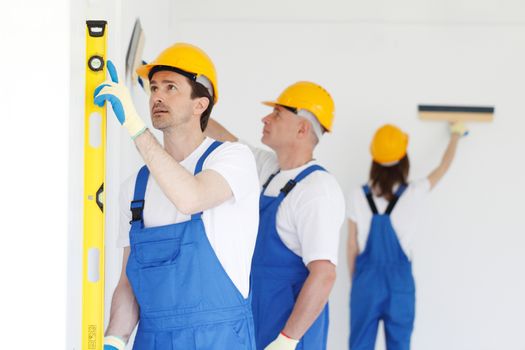 team of workmen painting wall