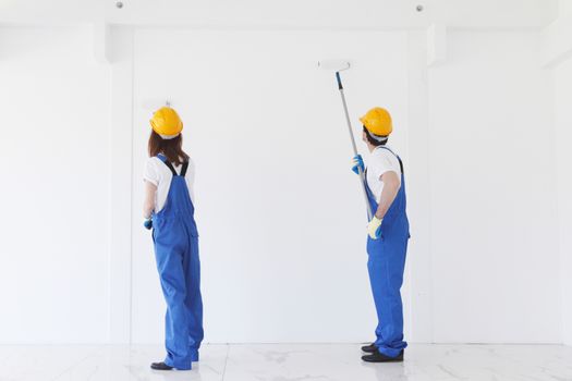 two workmen painting white wall