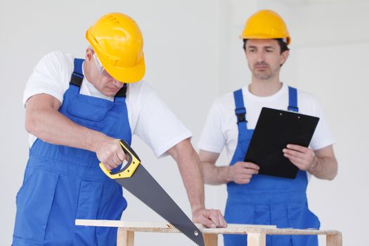 two workmen sawing wooden board