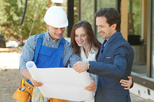 foreman shows house design plans to a young couple