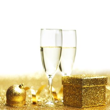 Champagne in glasses and gift box on golden background