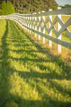  white fence leading up to a big red barn