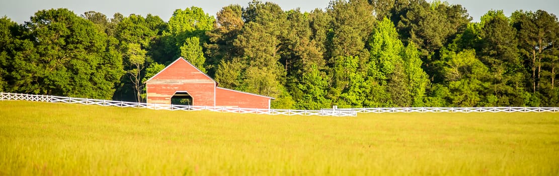  white fence leading up to a big red barn