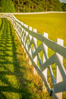  white fence leading up to a big red barn