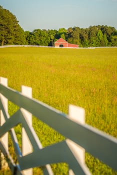  white fence leading up to a big red barn