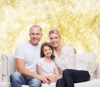 family, childhood, holidays and people concept - smiling mother, father and little girl over yellow lights background