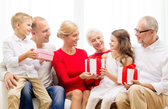 family, holidays, generation, christmas and people concept - smiling family with gift boxes sitting on couch at home