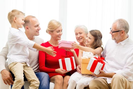 family, holidays, generation, christmas and people concept - smiling family with gift boxes sitting on couch at home