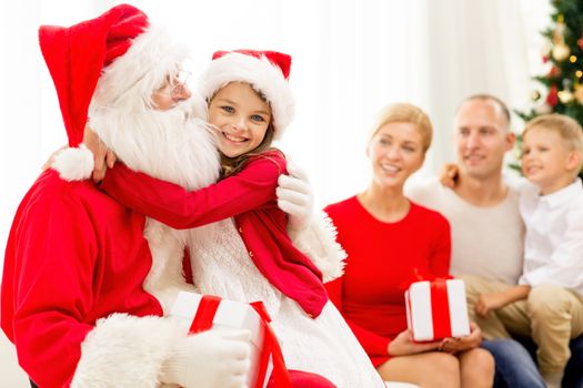 family, holidays, generation, christmas and people concept - smiling family with santa claus and gift boxes at home