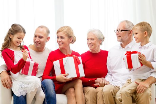 family, holidays, generation, christmas and people concept - smiling family with gift boxes sitting on couch at home