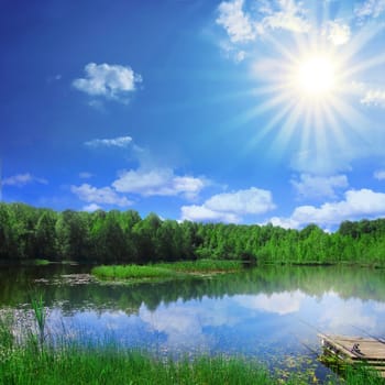 Rural landscape. Bright sun over the lake.