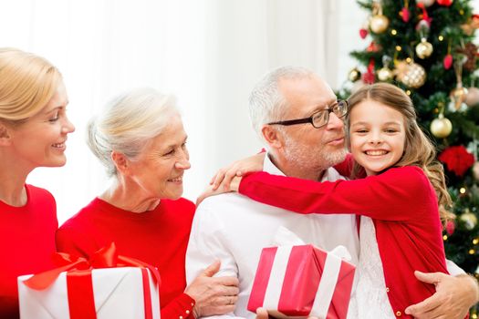 family, holidays, generation, christmas and people concept - smiling family with gift boxes sitting on couch at home