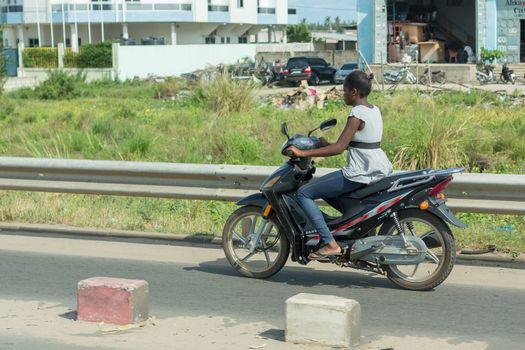 Cotonou, Benin: May 26: A woman rides a Motorcycle, the most common means of  transportation in the city, on May 26, 2015 in Cotonou, Benin.