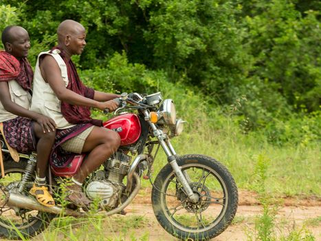 Morogoro, Tanzania: April 23: Two members of the Maasai tribe dressed in their distinct traditional clothing and riding a motorcycle - April 23, 2015 in Morogoro, Tanzania
