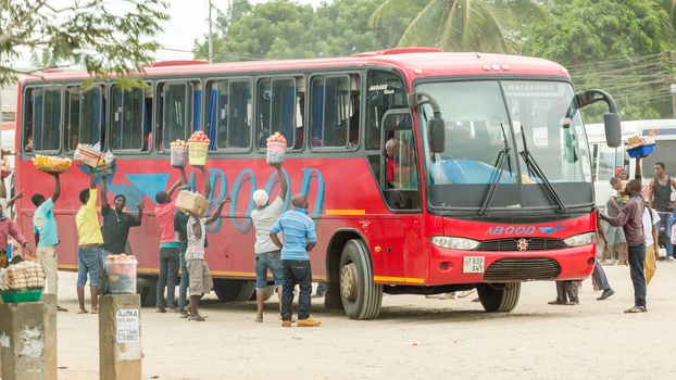 Dar Es Salaam: April 22: Street vendors surround a bus with merchandise to sell to its passengers, as it departs from the bus station, on April 22, 2015 in Dar Es Salaam, Tanzania