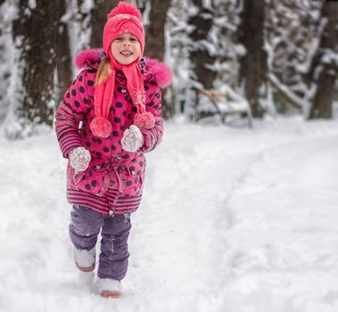 Happy 5 year old girl running on snow-covered park
