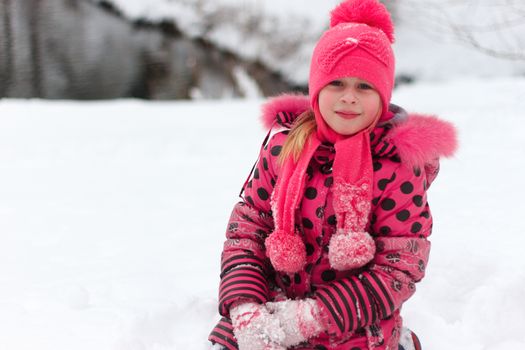 A little girl playing in a snow pile.