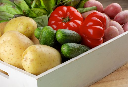Fresh Raw Potatoes, Cucumbers, Tomatoes and Butterhead Lettuce closeup in White Wooden Box 