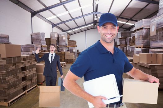 Happy delivery man with cardboard box and clipboard against forklift in a large warehouse