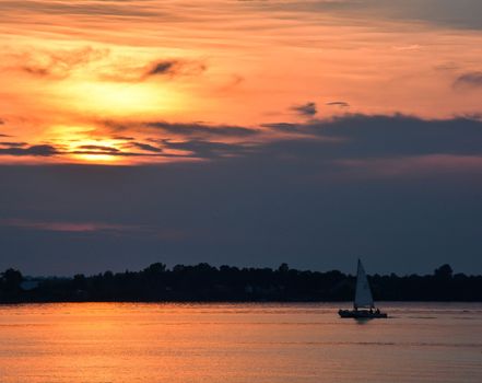 A sailboat sails into a dramatic sunset