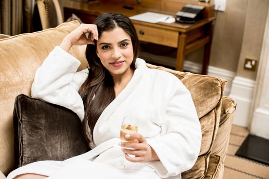 Relaxed woman laying in sofa with glass of champagne