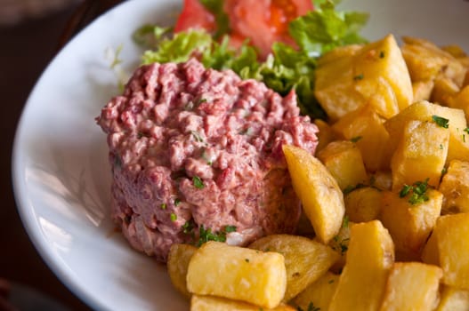 Tartare with fried potatoes, lettuce and tomato.