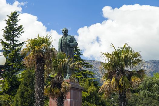 The monument to Lenin is among palm trees and against the bright blue sky