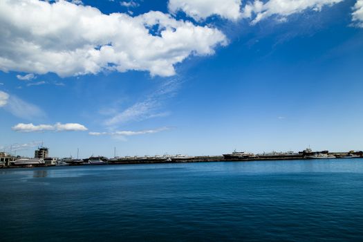 City bay with the ships in it under the blue sky and a bright sun