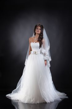 Young beautiful woman in a wedding dress on a studio background