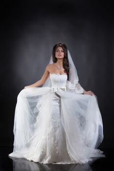 Young beautiful woman in a wedding dress on a studio background