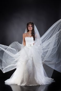 Young beautiful woman in a wedding dress on a studio background