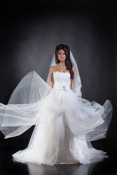 Young beautiful woman in a wedding dress on a studio background