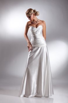 Young beautiful blonde woman in a wedding dress on a studio background