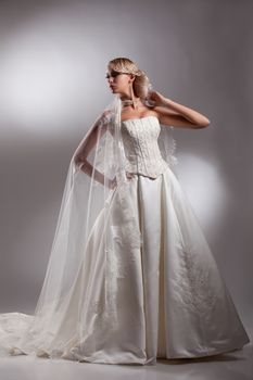 Young beautiful blonde woman in a wedding dress on a studio background