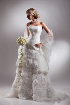 Young beautiful blonde woman in a wedding dress on a studio background