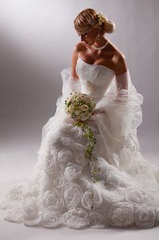 Young beautiful blonde woman in a wedding dress on a studio background