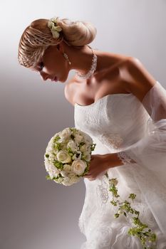 Young beautiful blonde woman in a wedding dress on a studio background