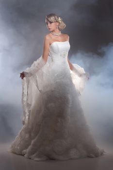 Young beautiful blonde woman in a wedding dress on a studio background