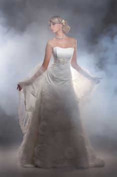 Young beautiful blonde woman in a wedding dress on a studio background