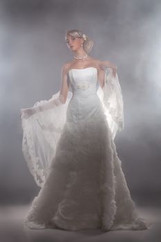 Young beautiful blonde woman in a wedding dress on a studio background