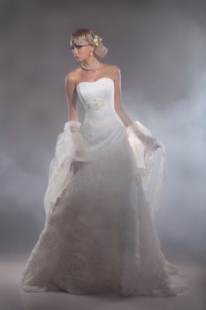Young beautiful blonde woman in a wedding dress on a studio background