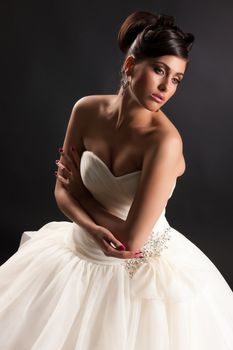 Young beautiful woman in a wedding dress on a black studio background