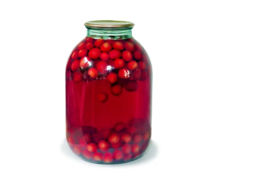 Home canning: a large glass cylinder with cherry compote, sealed metal lid. Presented on a white background..