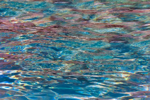 The surface of the water in the pool, sparkling with beautiful colored glare due to reflection of light. A background image.