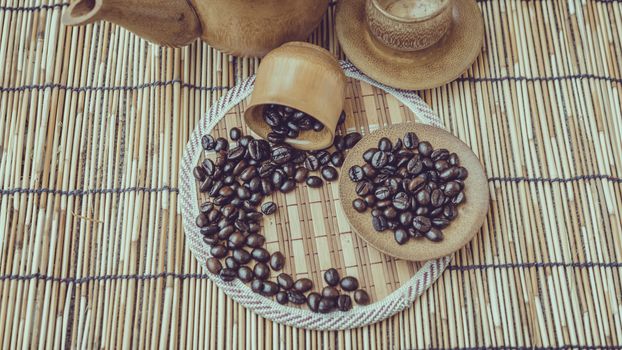 Coffee beans and coffee cup set on bamboo wooden background.Photo in retro color image style, Soft focus.